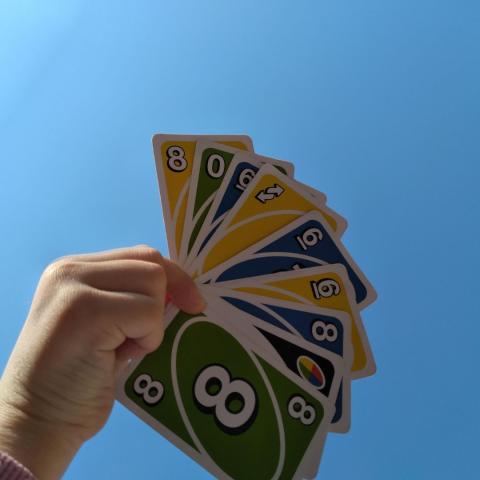 Cartes de Unon tenues dans une main avec pour fonds un ciel bleu
